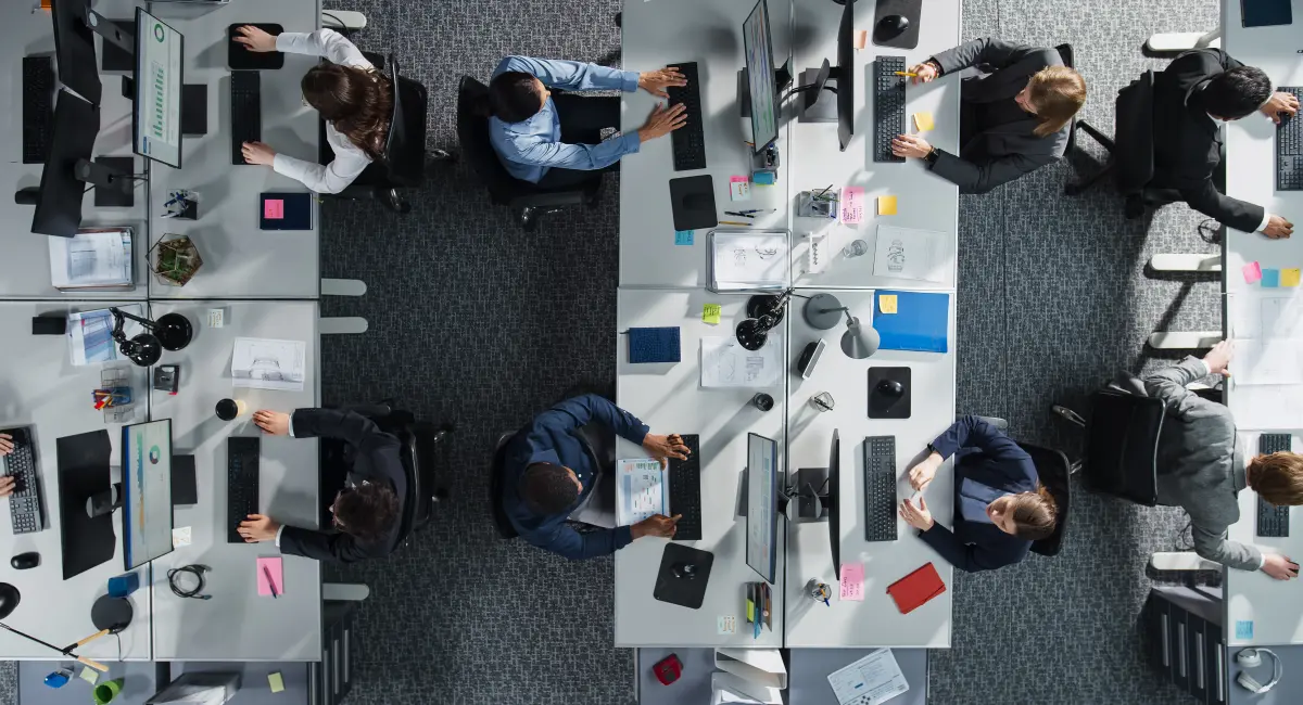 A bird’s eye view of a bank of office desks, with people working on computers