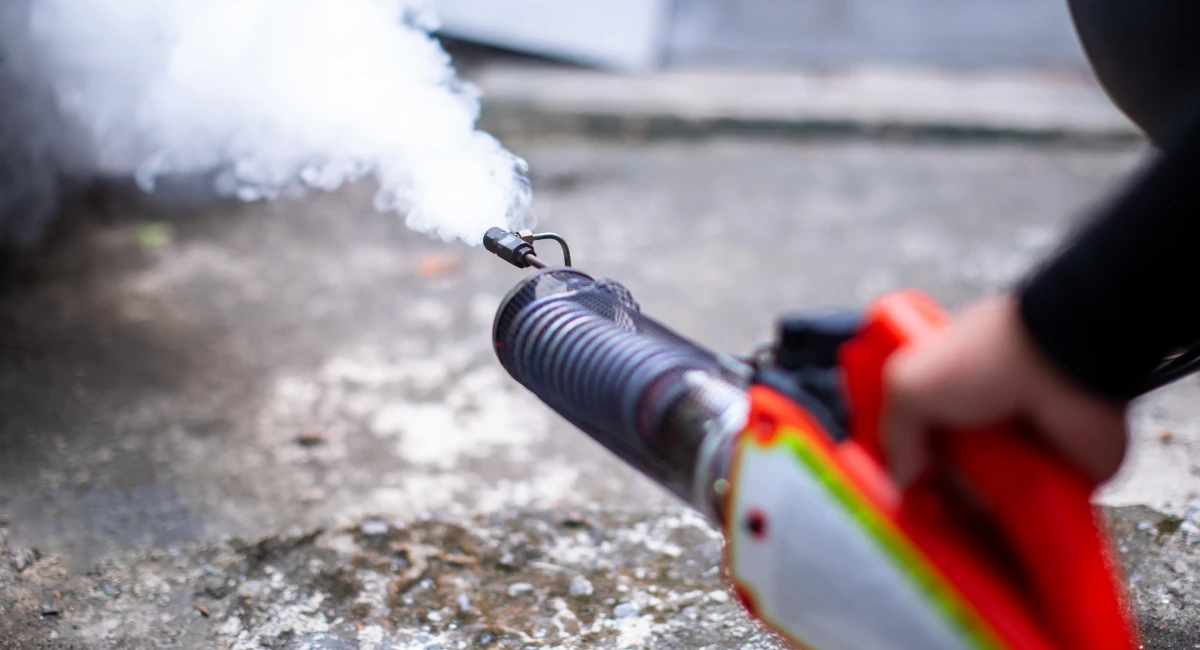 A man using a fogging machine to treat for mosquitoes