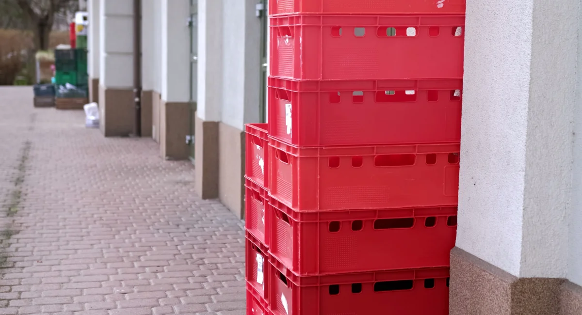 A stack of red plastic food crates on a loading ramp behind a grocery store